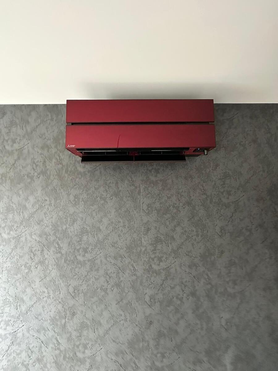 Rote Klimaanlage an grauer Wand; schlichtes modernes Design.